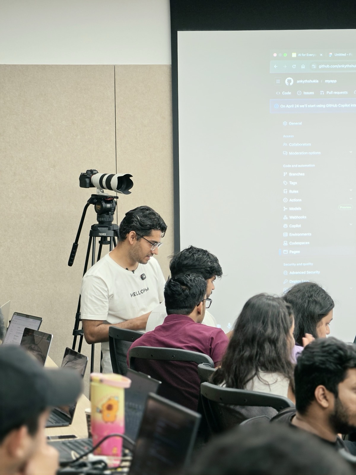 A HelloPM member filming a live AI build session projected on the screen