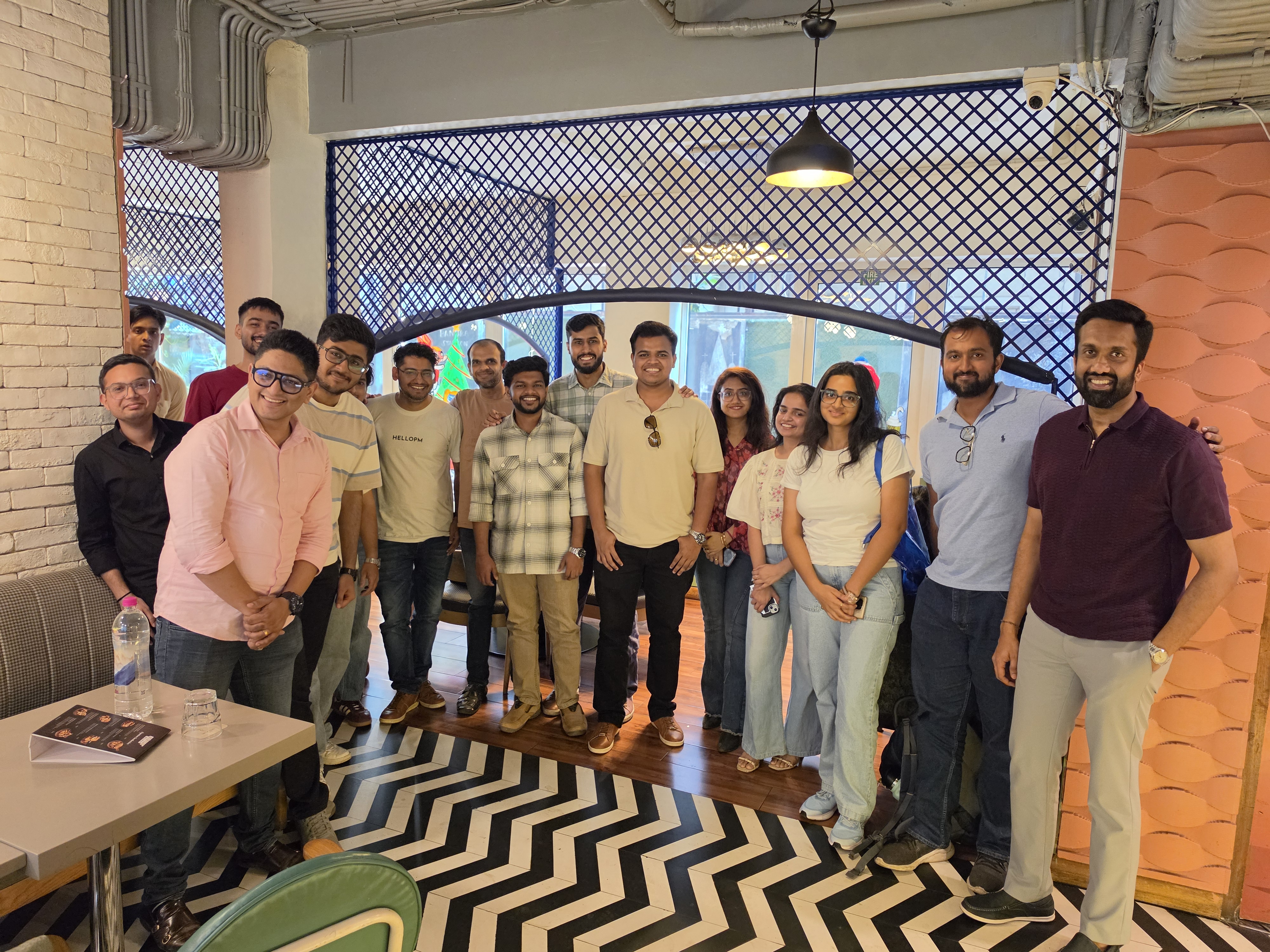 HelloPM community group photo in a Mumbai cafe with chevron flooring