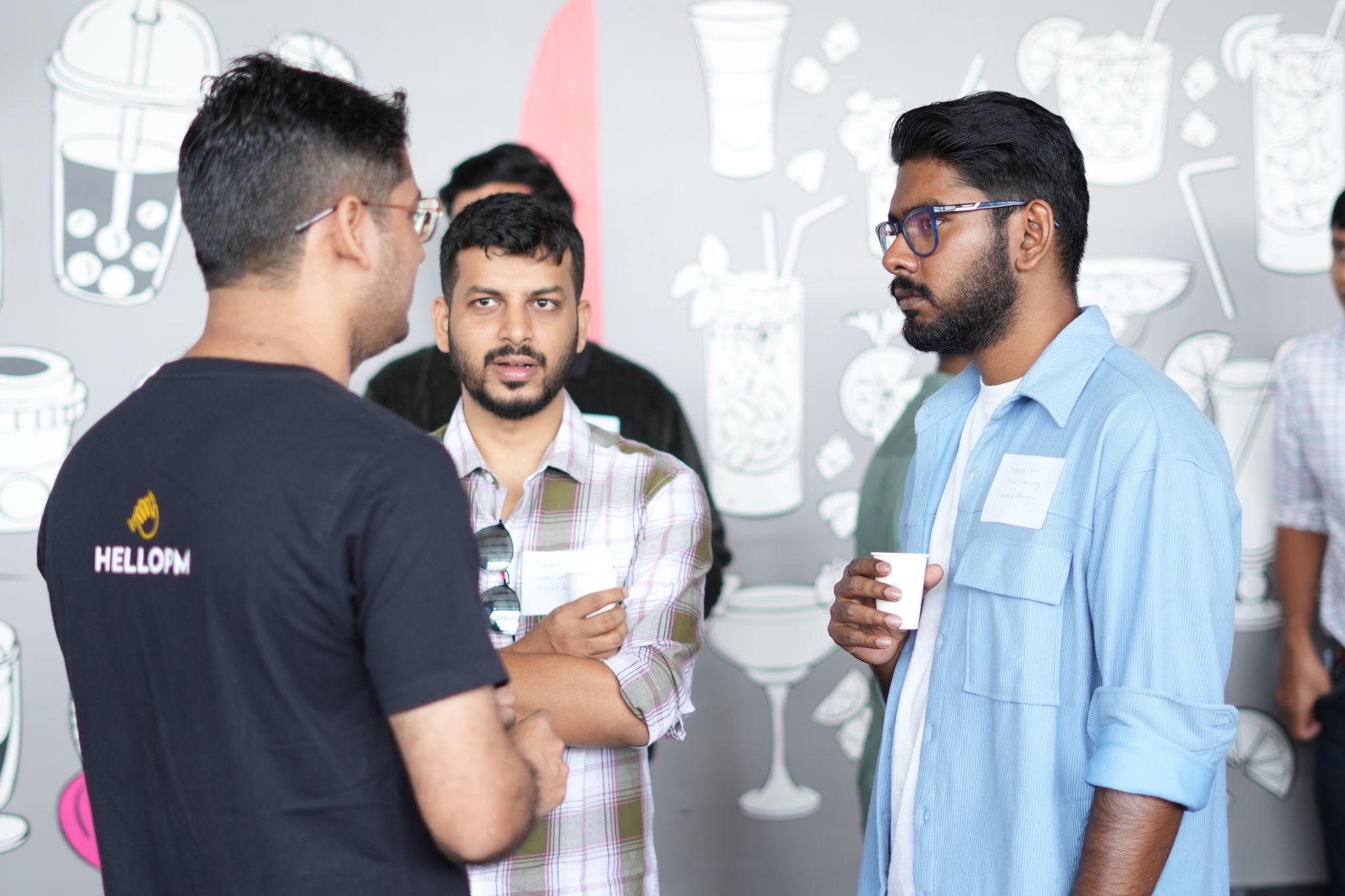 Three HelloPM members in conversation over coffee at a meetup