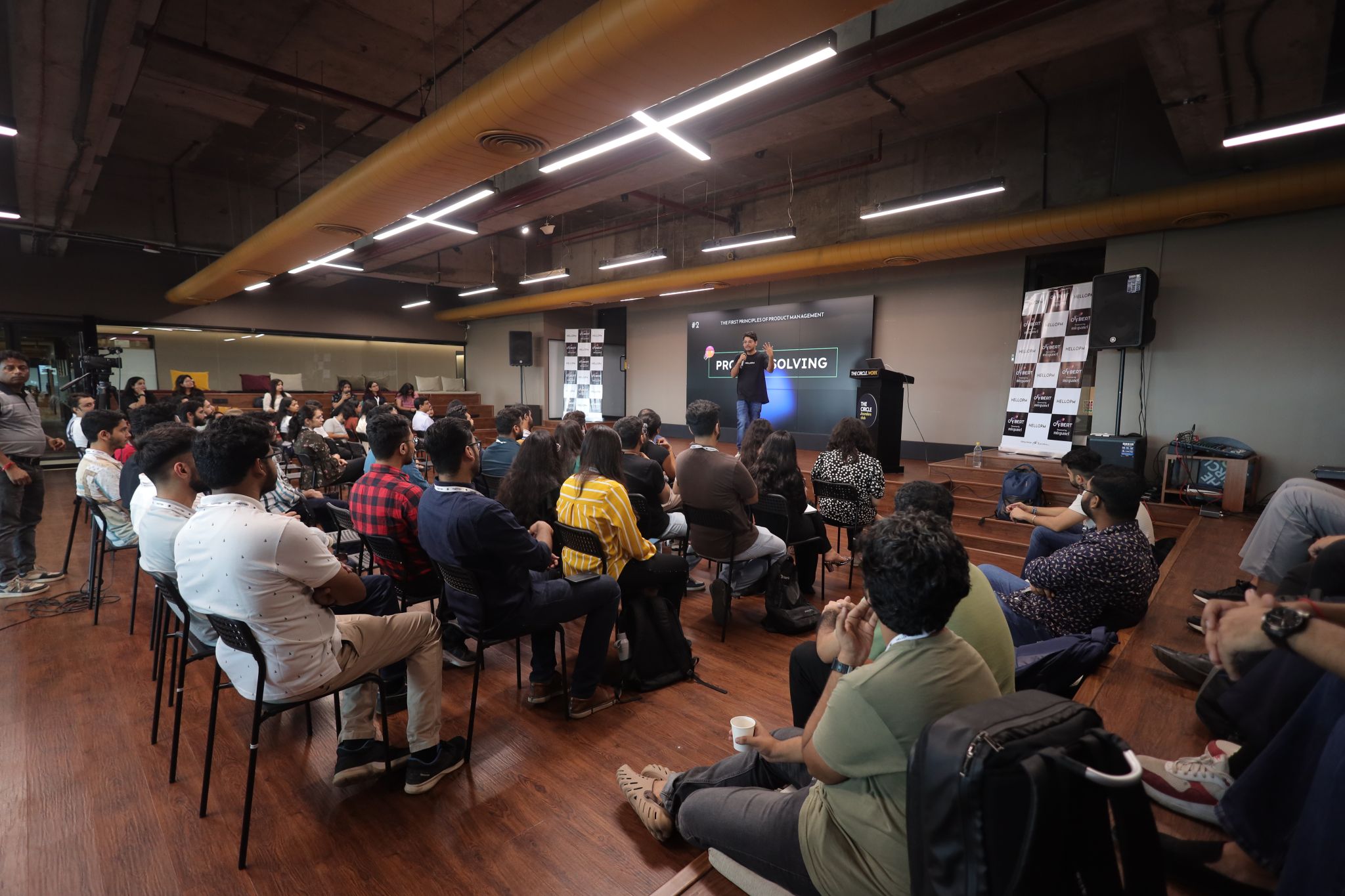A full audience at a HelloPM session with 'Problem Solving' on the stage screen